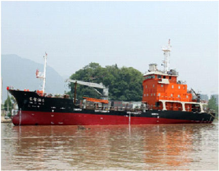 A red cargo vessel is pictured against a backdrop of trees.