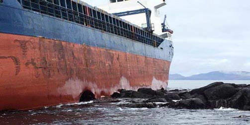 The Kaami's rusted and broken hull is seen against rocks from below