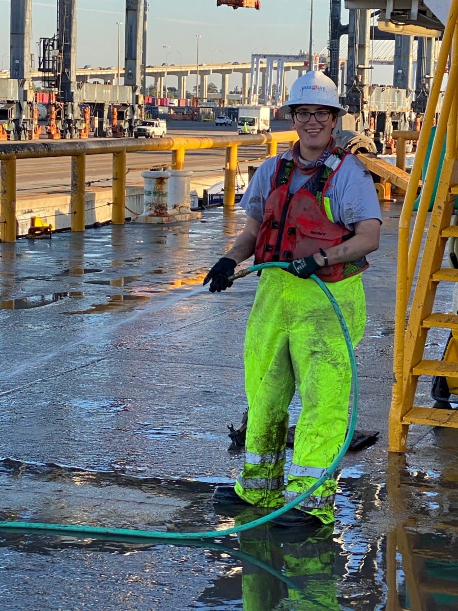Resolve Marine employee smiling holding hose on jobsite wearing Personal Protective Equipment (PPE).